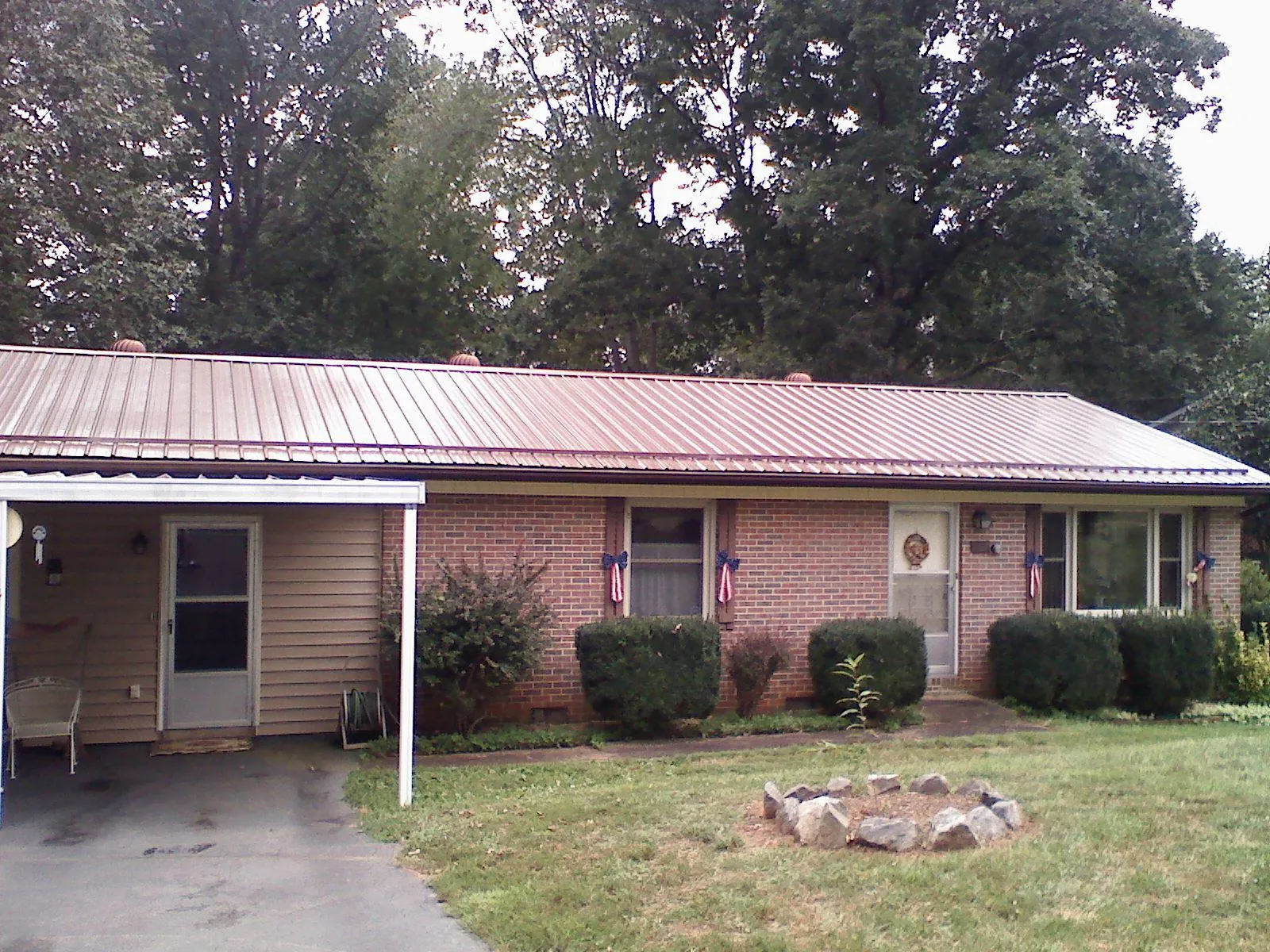 Bronze metal roof and carport on a brick ranch home — Roof Repair work by our crew in Bryan