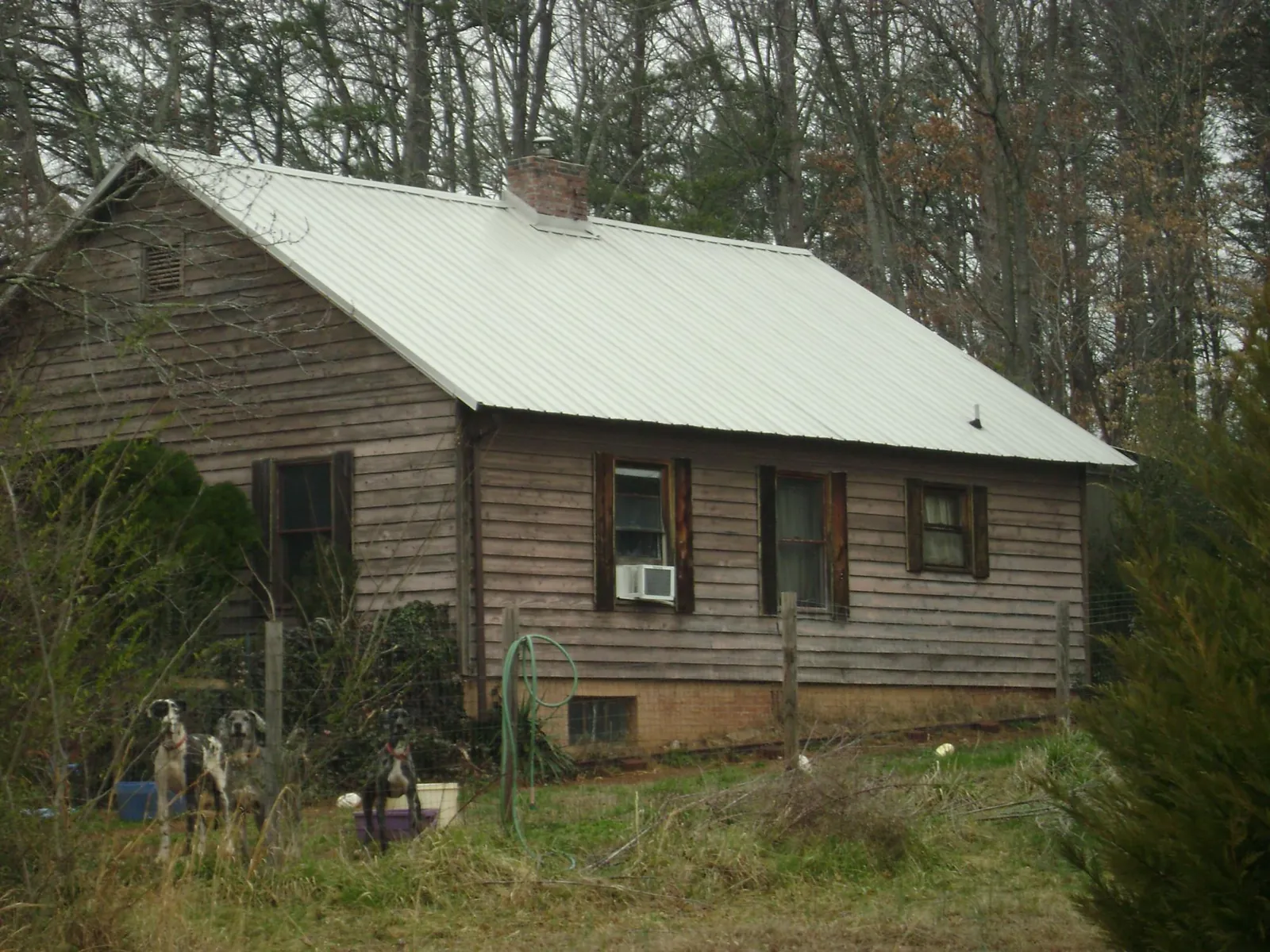 White metal roof on an old wood sided farmhouse, from a Asphalt Shingle Roof Repair job in Bryan